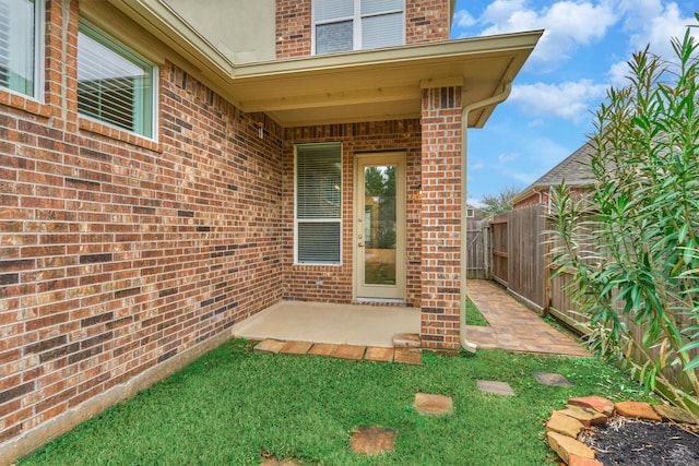 entrance to property featuring a patio and a lawn