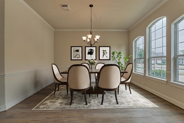 dining area with ornamental molding, hardwood / wood-style floors, and a notable chandelier