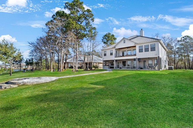 rear view of house featuring a patio, a balcony, and a lawn