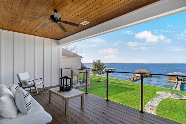 wooden terrace with a water view, a yard, outdoor lounge area, and ceiling fan