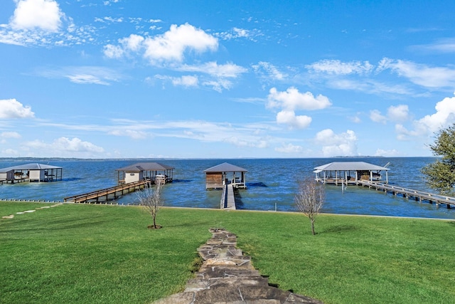 view of dock with a lawn and a water view