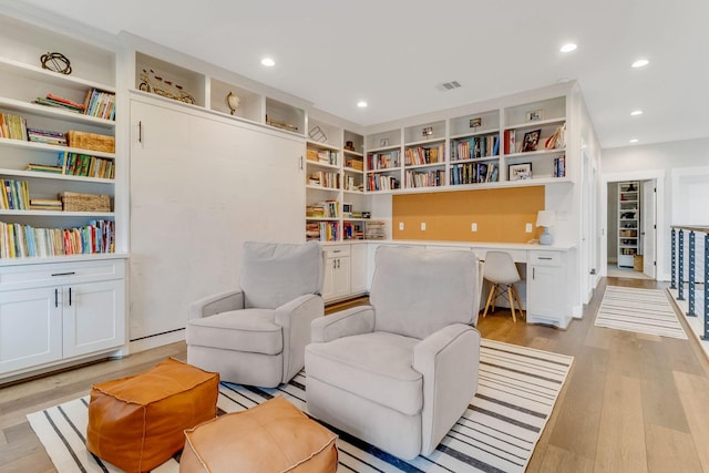 sitting room featuring built in desk and light hardwood / wood-style floors