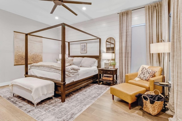 bedroom featuring wood-type flooring, ceiling fan, and wood walls