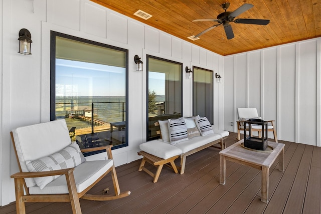 wooden deck with a water view and ceiling fan