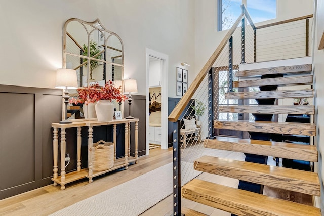 stairs with hardwood / wood-style flooring, a healthy amount of sunlight, and a high ceiling