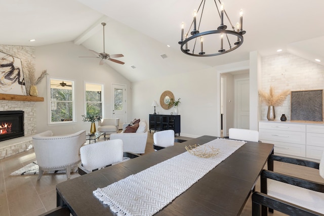 dining space with beamed ceiling, a stone fireplace, and high vaulted ceiling