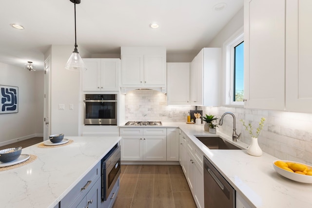 kitchen featuring sink, white cabinetry, stainless steel appliances, light stone countertops, and decorative light fixtures