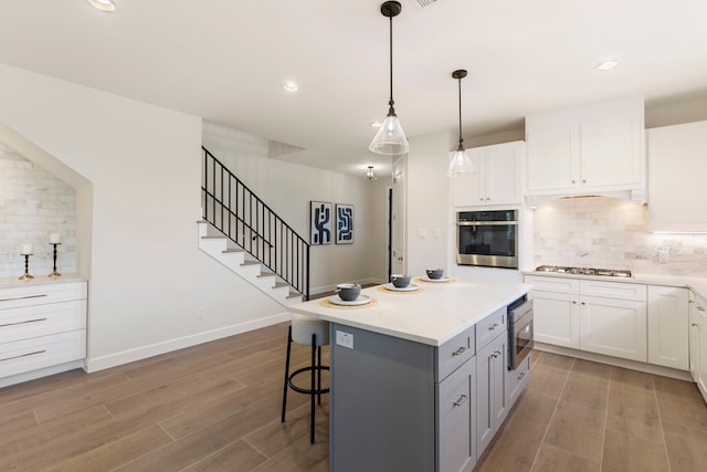 kitchen with white cabinetry, appliances with stainless steel finishes, a kitchen bar, and pendant lighting