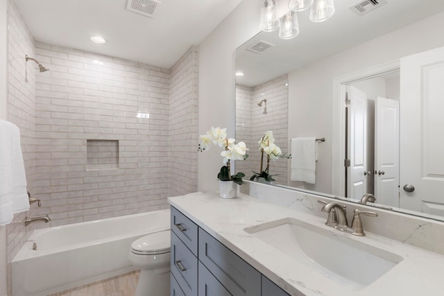 full bathroom with vanity, tiled shower / bath, and toilet