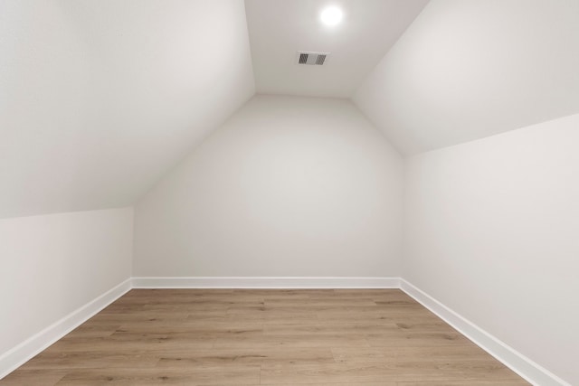 additional living space featuring vaulted ceiling and light hardwood / wood-style flooring