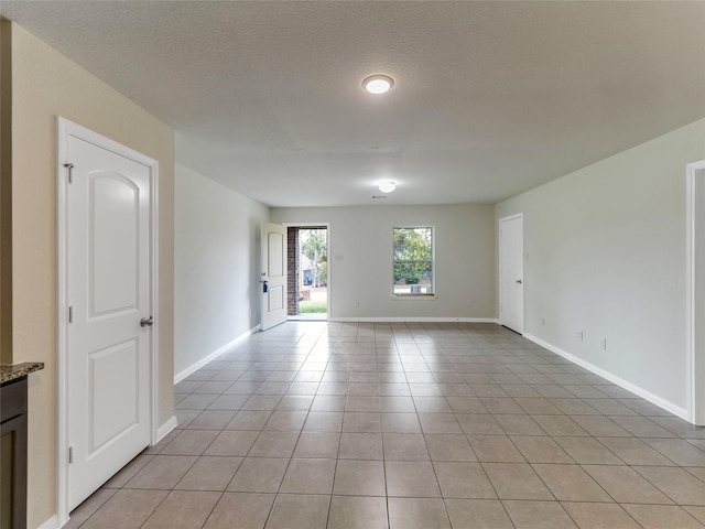 empty room with light tile patterned floors and a textured ceiling