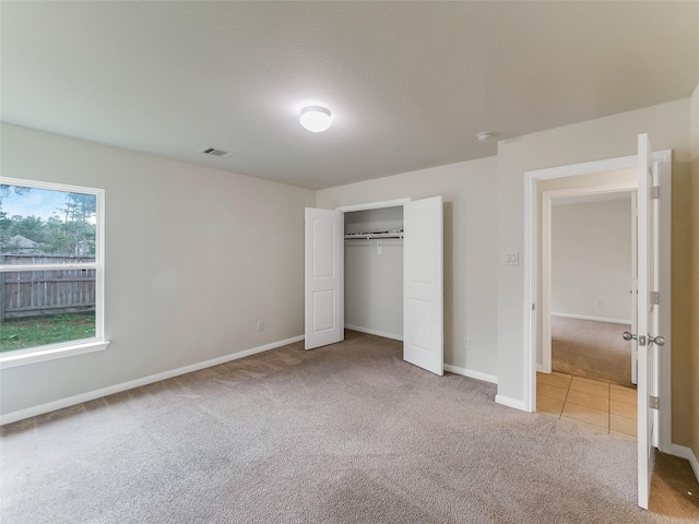 unfurnished bedroom with light colored carpet and a closet