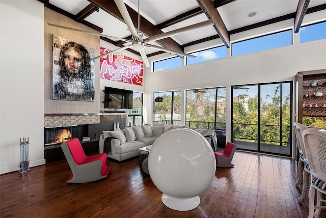 interior space with dark hardwood / wood-style flooring, beam ceiling, ceiling fan, and a towering ceiling