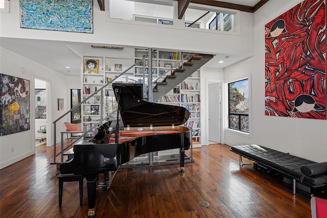 misc room with hardwood / wood-style flooring, a towering ceiling, and built in shelves