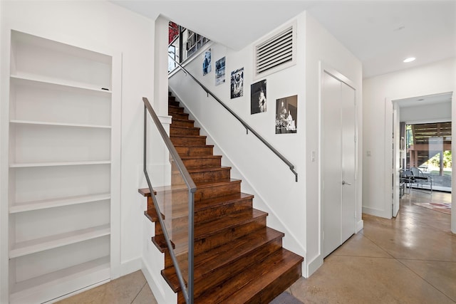 stairs featuring built in shelves and concrete flooring