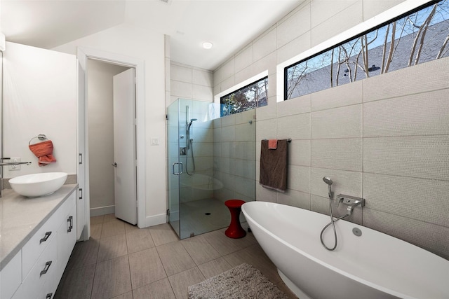 bathroom featuring vanity, tile patterned flooring, plus walk in shower, and tile walls