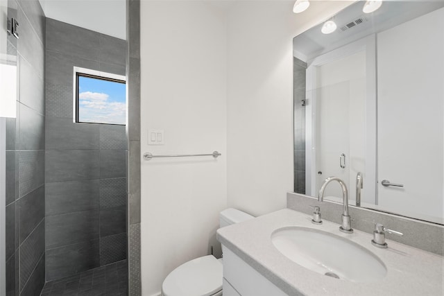 bathroom featuring tiled shower, vanity, and toilet