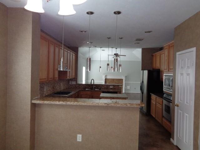 kitchen with pendant lighting, sink, light stone counters, black appliances, and kitchen peninsula