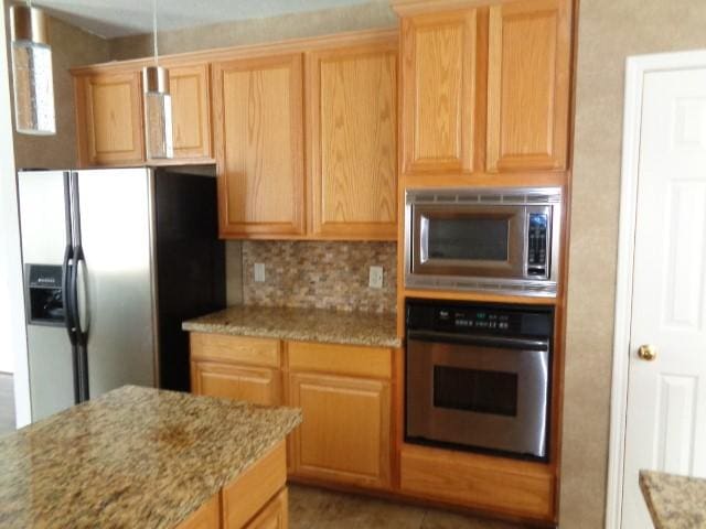 kitchen with light stone counters, backsplash, and appliances with stainless steel finishes