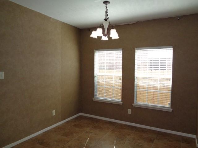 unfurnished room featuring dark tile patterned floors and a chandelier