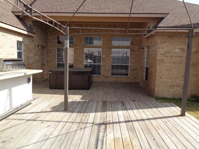 deck with a hot tub, an outdoor kitchen, and grilling area