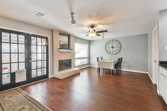 interior space featuring a fireplace, dark hardwood / wood-style flooring, ceiling fan, a textured ceiling, and french doors