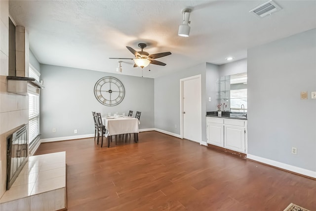 unfurnished dining area with ceiling fan, sink, hardwood / wood-style floors, and a fireplace