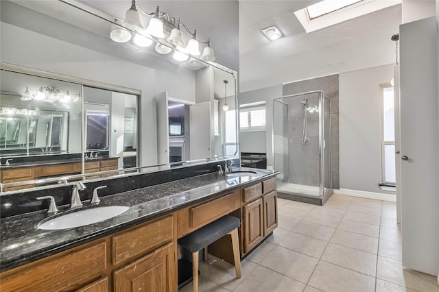 bathroom with vanity, tile patterned floors, a skylight, and a shower with door