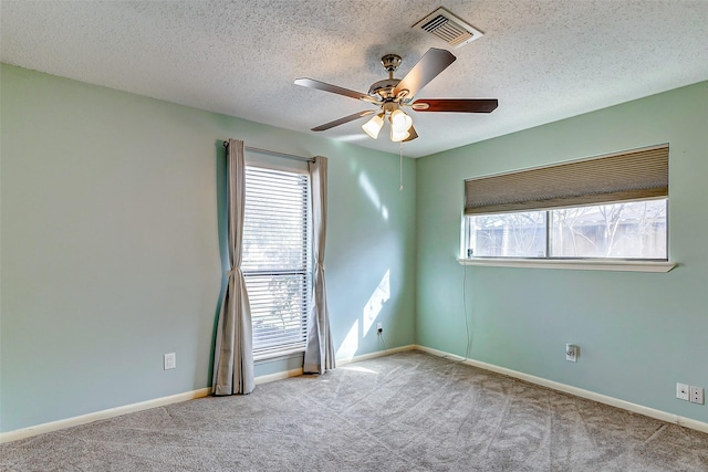 unfurnished room with a textured ceiling, light colored carpet, and ceiling fan