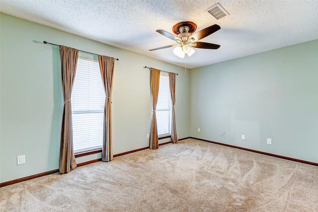 spare room featuring ceiling fan, light colored carpet, and a textured ceiling