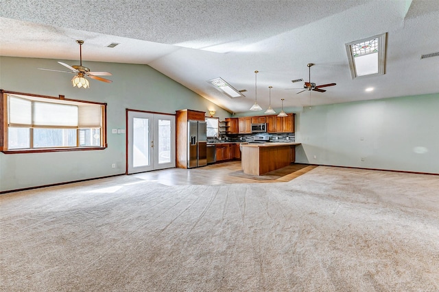 kitchen with hanging light fixtures, light carpet, ceiling fan, and stainless steel appliances