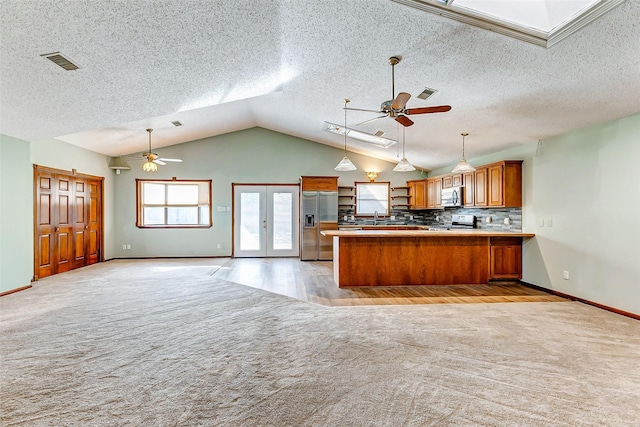 kitchen featuring a skylight, appliances with stainless steel finishes, light carpet, and kitchen peninsula