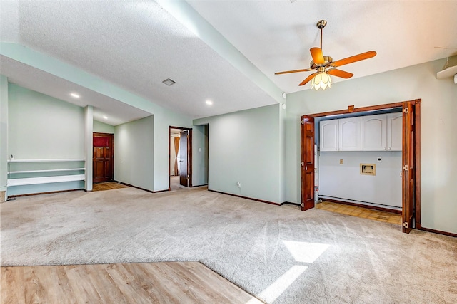 carpeted empty room featuring ceiling fan, vaulted ceiling, and a textured ceiling