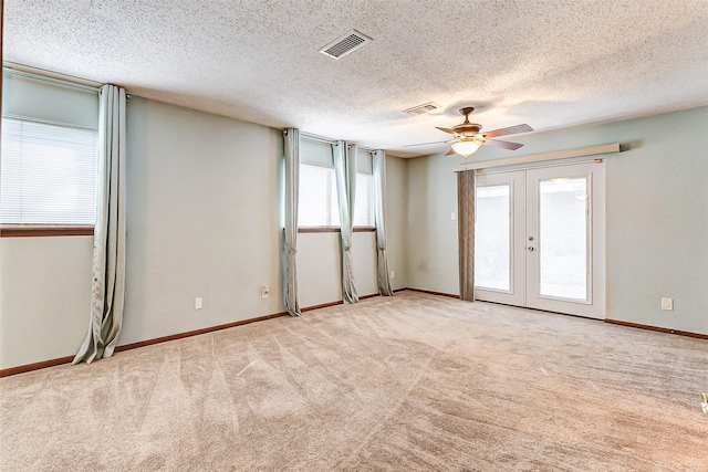 spare room with light carpet, a textured ceiling, french doors, and ceiling fan