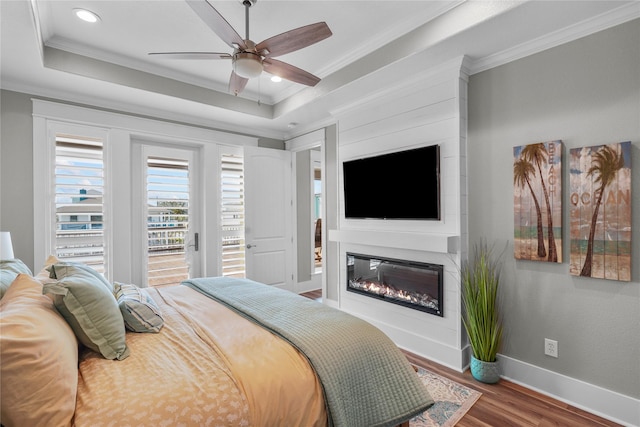 bedroom with ceiling fan, ornamental molding, a raised ceiling, and wood-type flooring