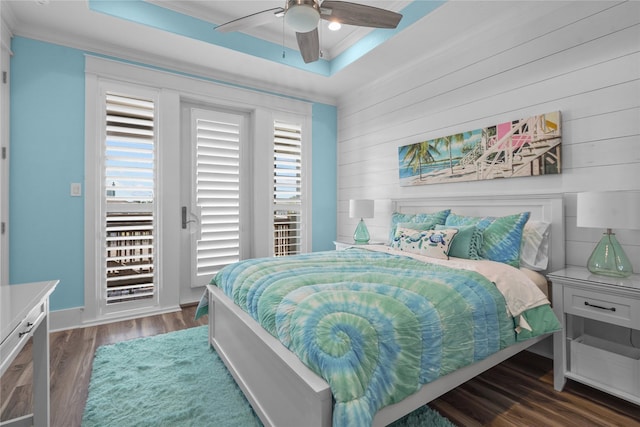 bedroom featuring dark hardwood / wood-style floors, access to exterior, ceiling fan, a raised ceiling, and crown molding