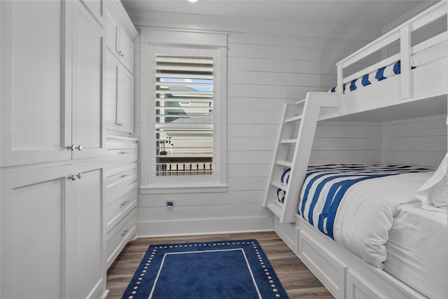 bedroom featuring ornamental molding, dark hardwood / wood-style floors, and wooden walls