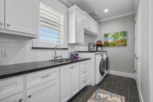 laundry area featuring sink, dark tile patterned flooring, cabinets, washing machine and clothes dryer, and crown molding