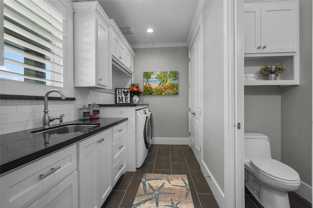 kitchen featuring washer and dryer, tasteful backsplash, sink, white cabinets, and ornamental molding