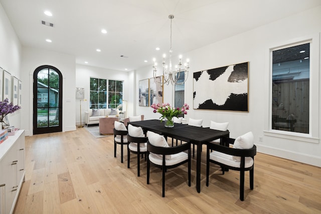 dining space with light hardwood / wood-style flooring and a chandelier