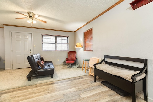 sitting room with ornamental molding, ceiling fan, a textured ceiling, and light wood-type flooring