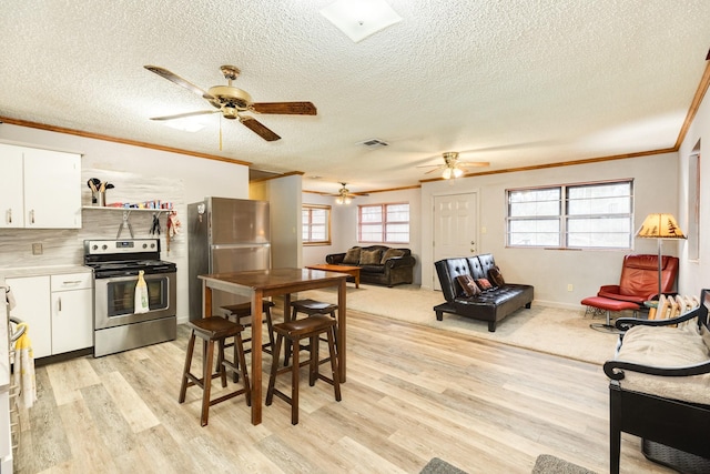 dining area with light hardwood / wood-style flooring, ornamental molding, and a textured ceiling