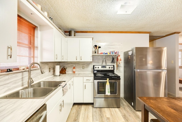 kitchen with tasteful backsplash, white cabinetry, sink, stainless steel appliances, and light wood-type flooring