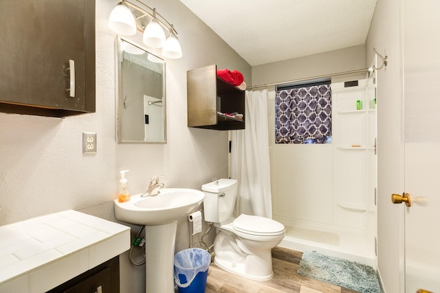 bathroom featuring sink, hardwood / wood-style floors, a textured ceiling, curtained shower, and toilet