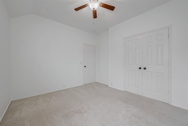 unfurnished bedroom with ceiling fan, a closet, lofted ceiling, and light carpet