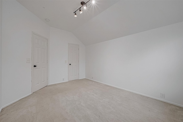 additional living space featuring vaulted ceiling and light colored carpet