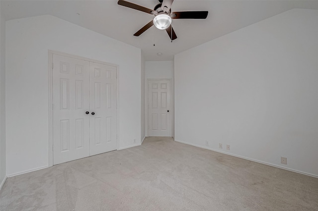 unfurnished bedroom with light carpet, vaulted ceiling, a closet, and ceiling fan