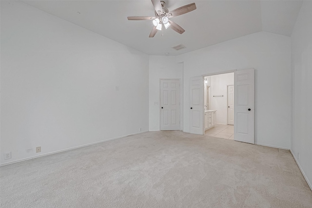 unfurnished bedroom featuring lofted ceiling, light colored carpet, ceiling fan, and ensuite bathroom