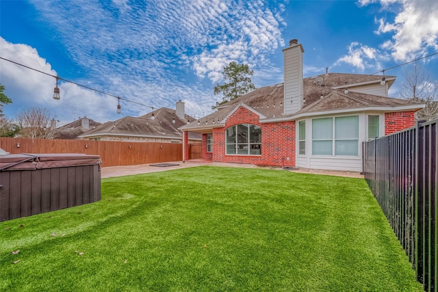 rear view of house with a yard and a hot tub