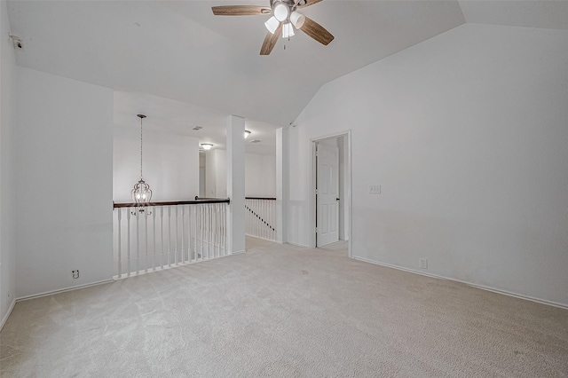 empty room featuring light colored carpet, lofted ceiling, and ceiling fan with notable chandelier